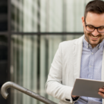 Professional marketer standing outdoors with a tablet, used as the header image for an article about Gary Halbert’s 10 email copywriting rules.